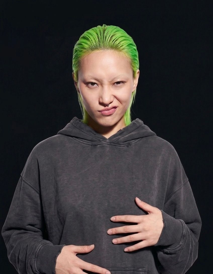 probably Not Sorry|Unapologetic Sarcasm Person with bright green hair making a playful, slightly mischievous expression.